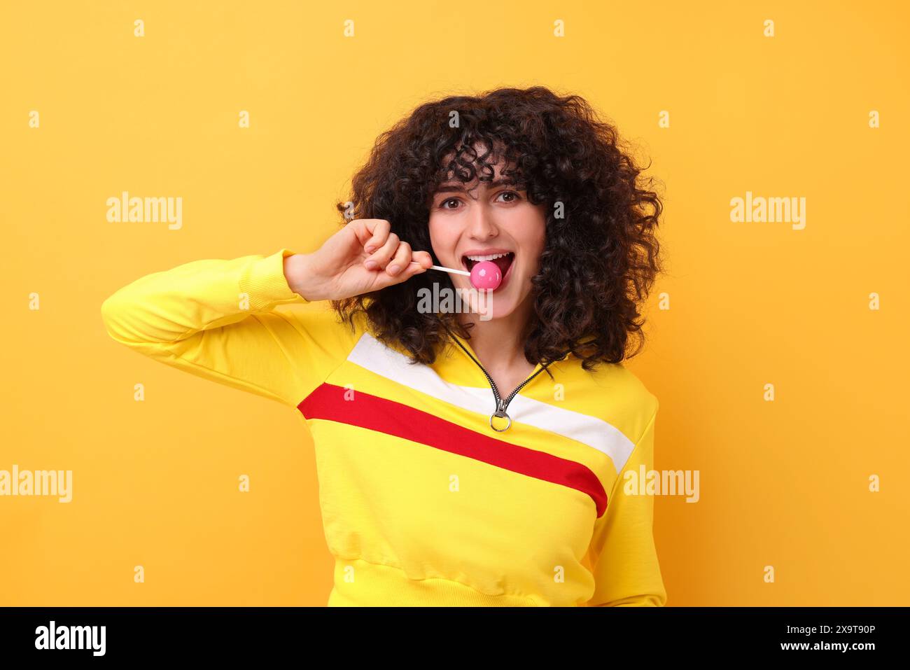 Beautiful woman with lollipop on yellow background Stock Photo