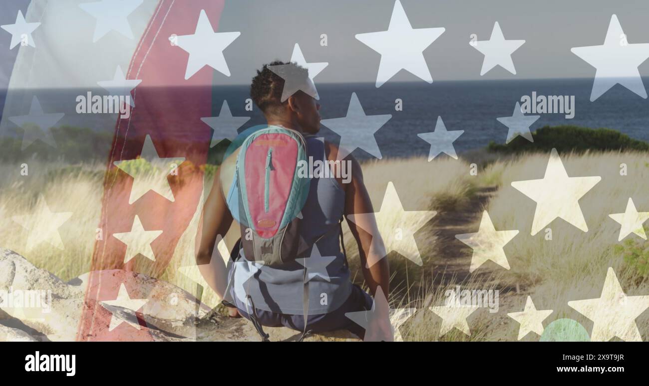 Image of american flag over african american man sitting in mountains Stock Photo