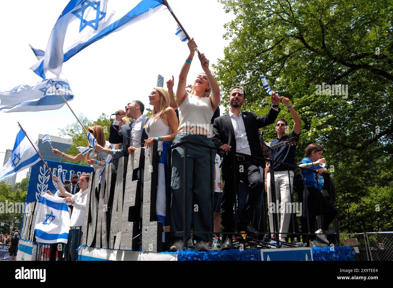 Parade participants wave the Israeli flags while standing on a float on Fifth Avenue at the 59th