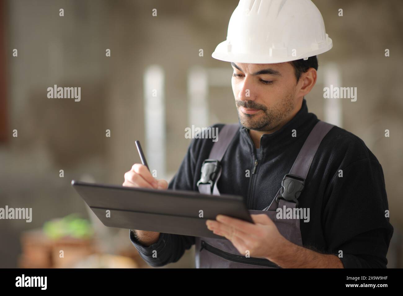 Construction worker using digital tablet to take notes working in a house Stock Photo