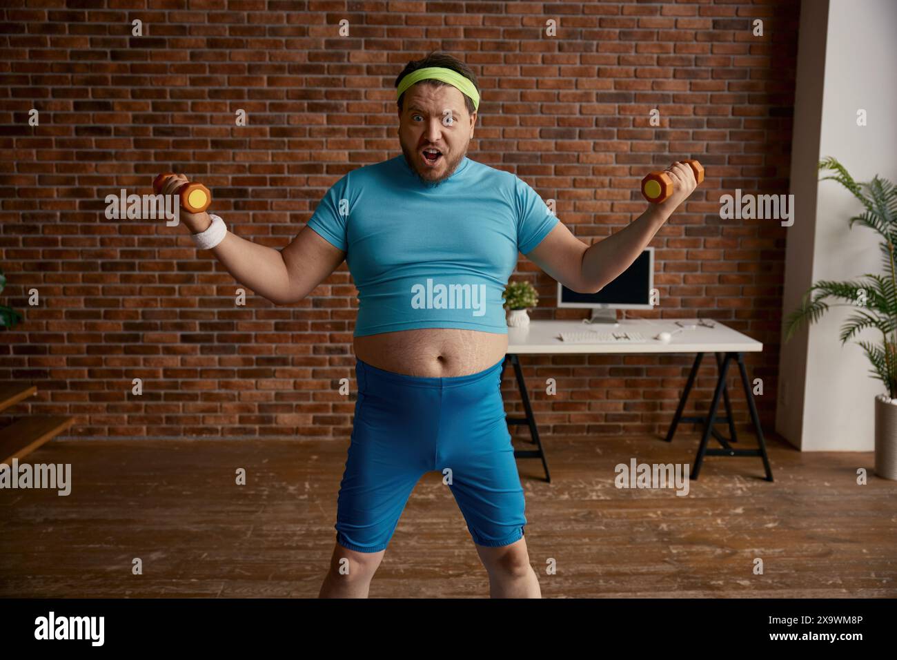 Portrait of serious comic man with obese figure doing workout with dumbbells Stock Photo