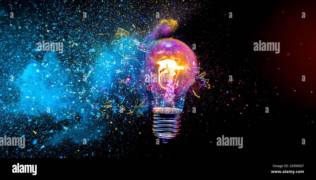 Light bulb exploding with colorful powder on a black background Stock Photo