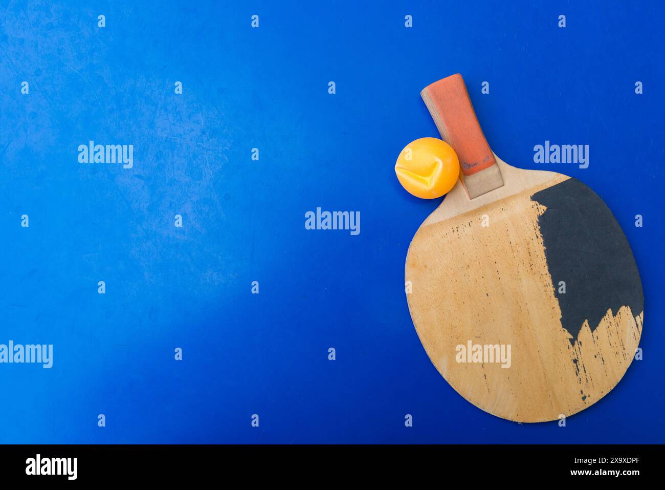 old pingpong rackets and a dented ball on a blue pingpong table Stock Photo