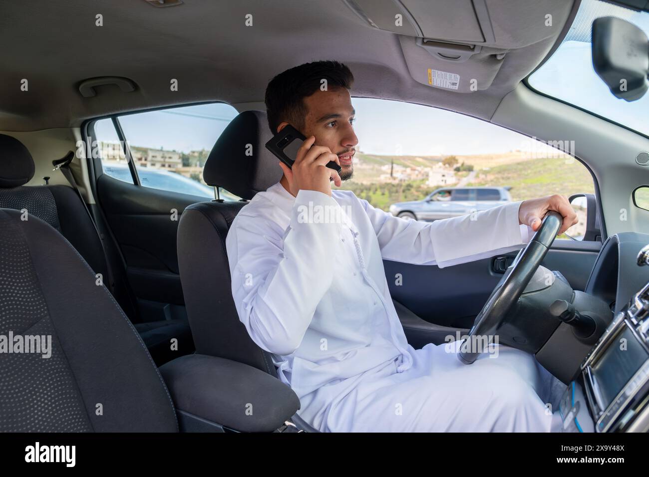 Young arab male using mobile phone while driving Stock Photo - Alamy