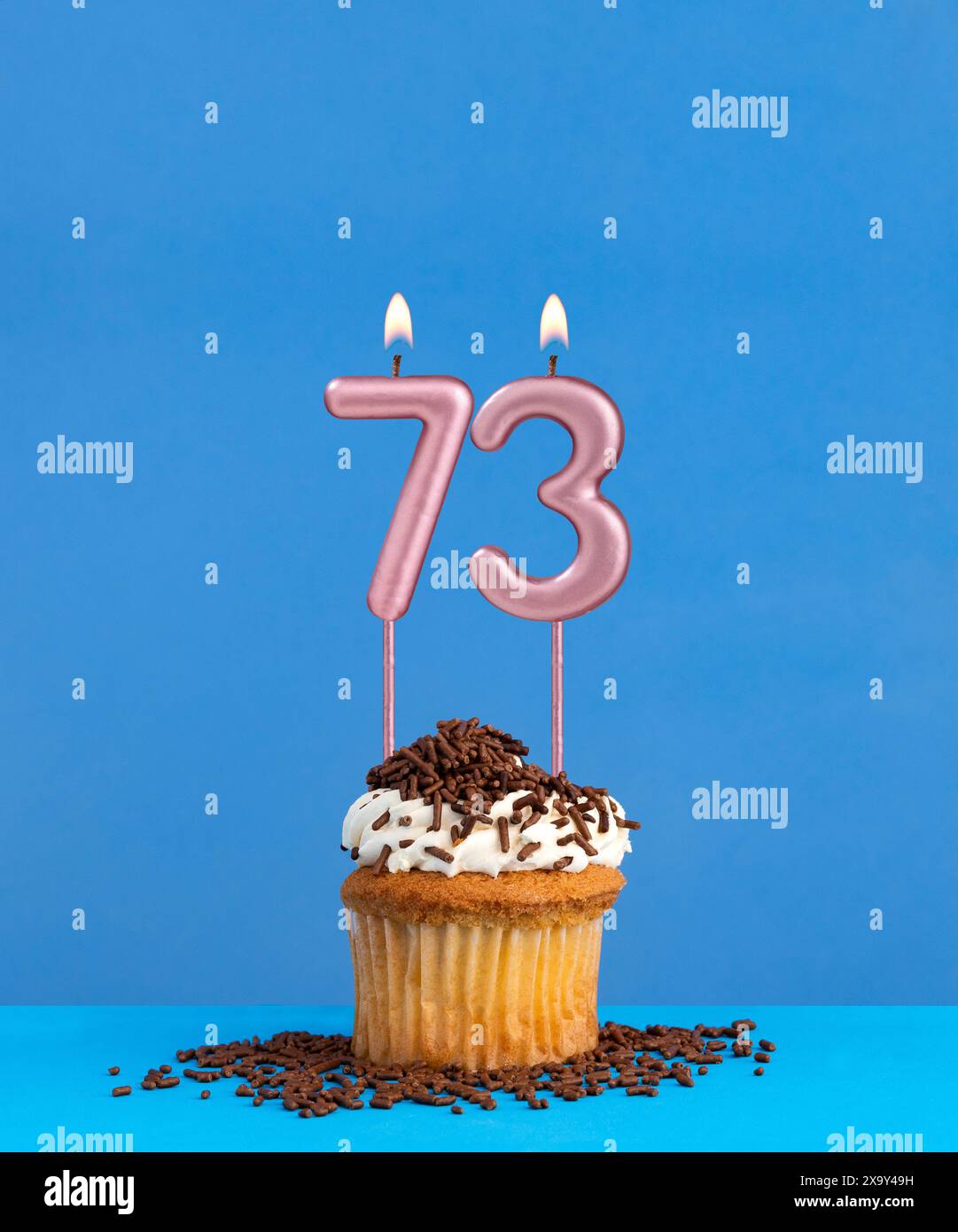 Birthday candle with cupcake on blue background - Number 73 Stock Photo