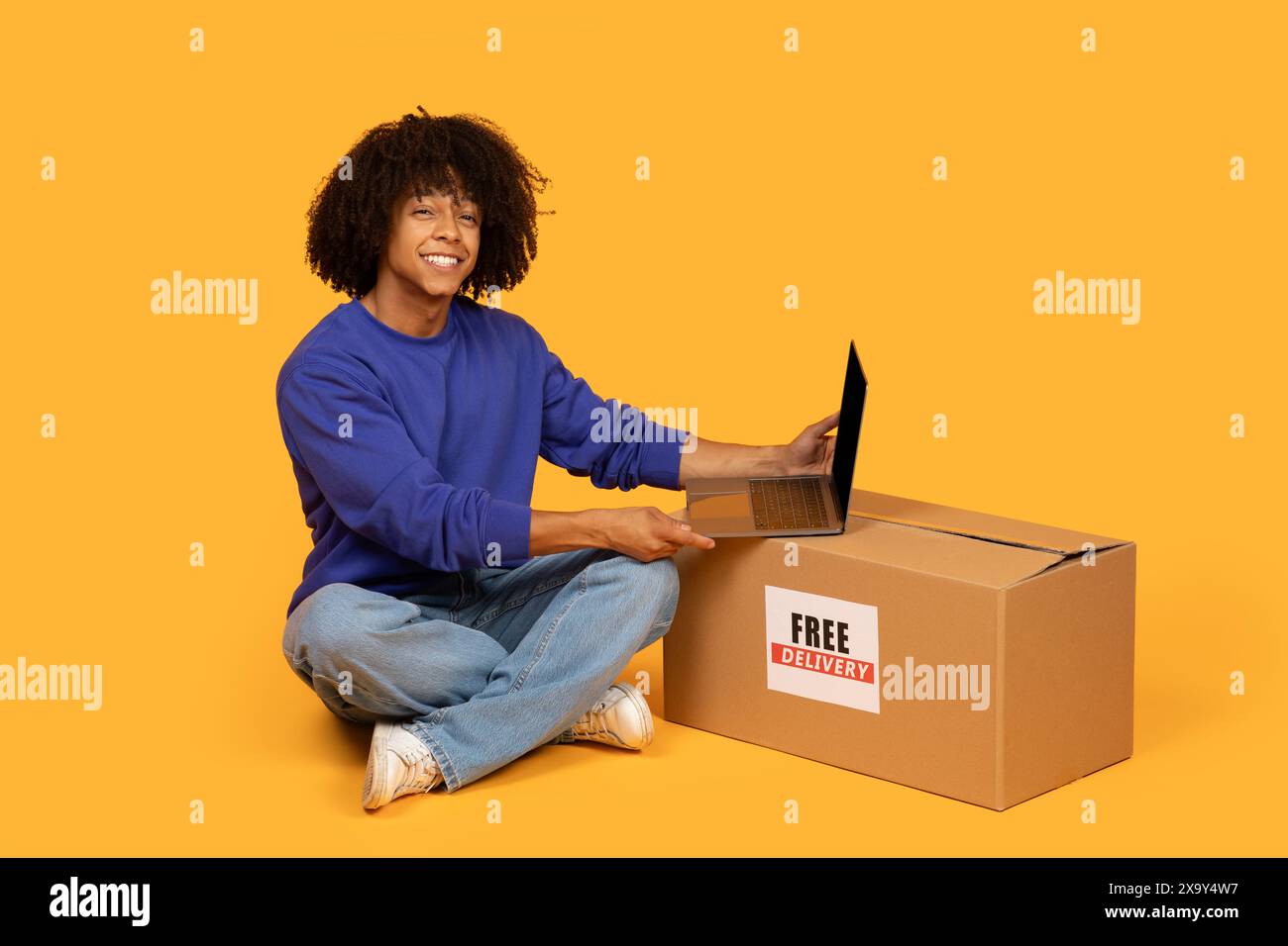 Guy Sitting on Floor With Box and Laptop Stock Photo