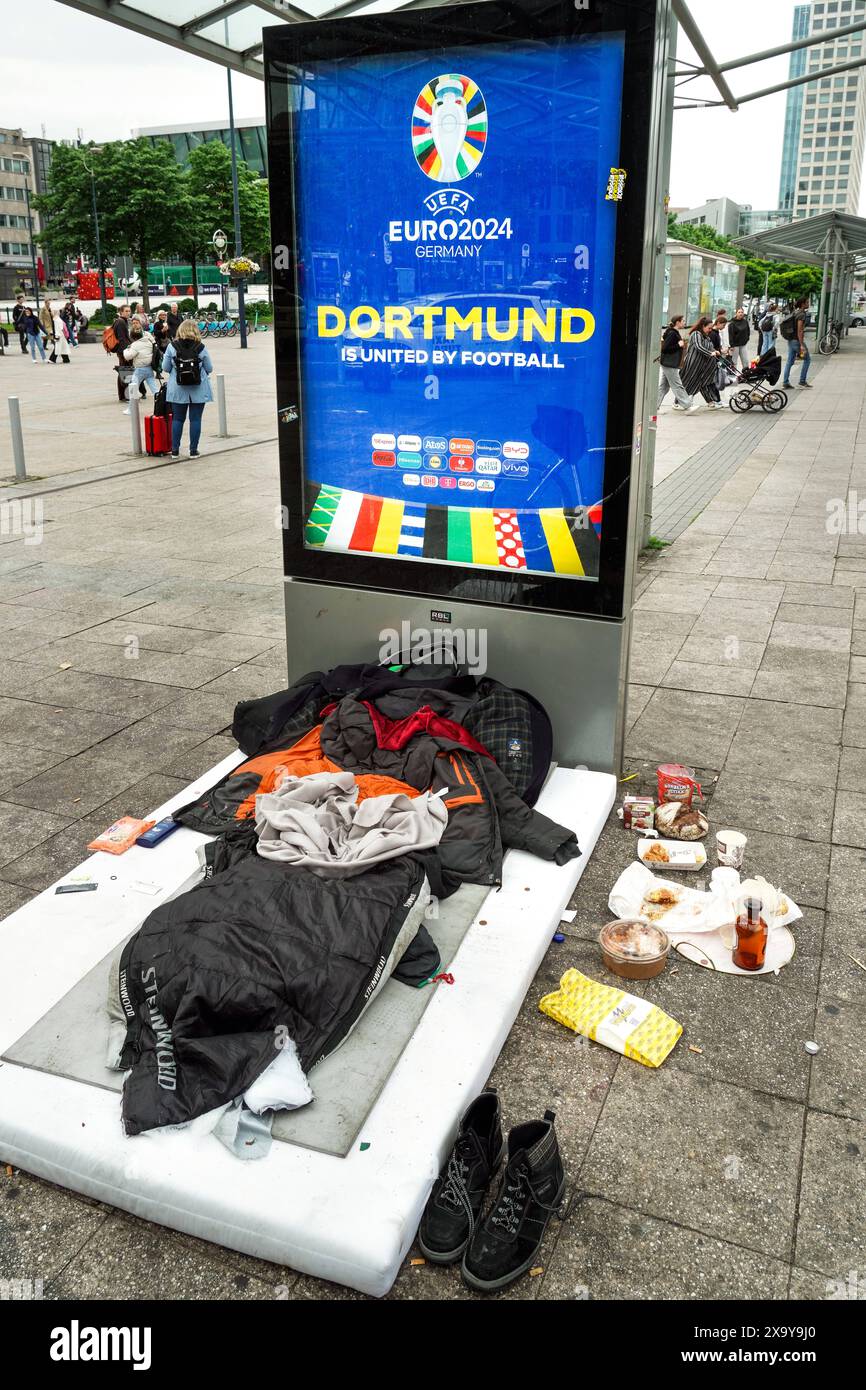 Schlafplatz eines Wohnungslosen vor einem Willkommensschild Display zur