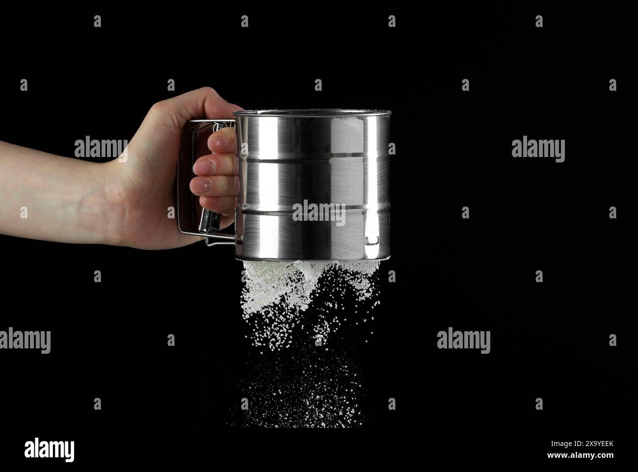 Woman sieving flour against black background, closeup. Space for text ...
