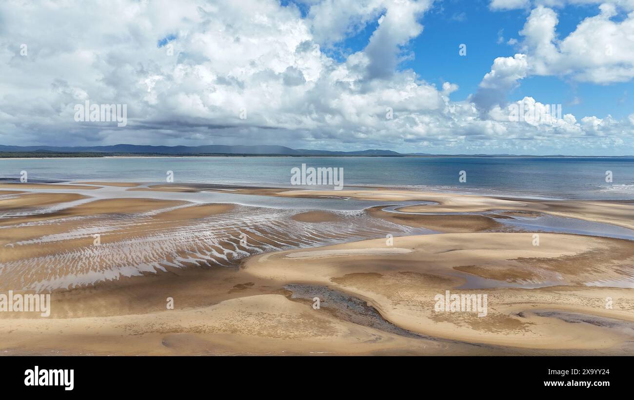 A scenic beach landscape with mountains in the distance, blue sky, and ...