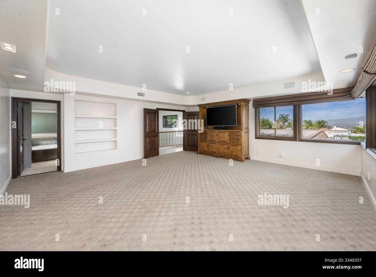 An empty room with ocean view through large windows, carpeted floor in