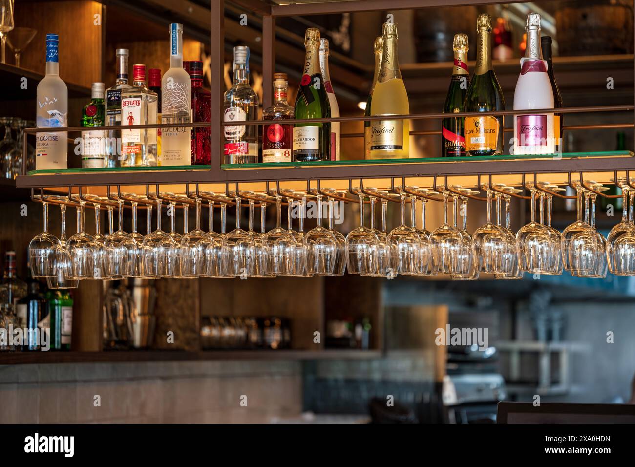 A well-stocked bar with numerous bottles and glasses hanging upside down Stock Photo