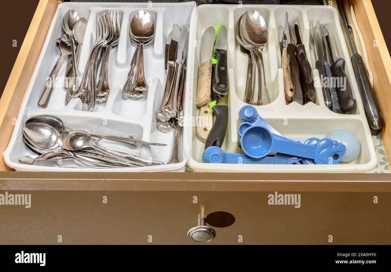 Horizontal shot of the cluttered silverware drawer in elderly people’s home. Stock Photo