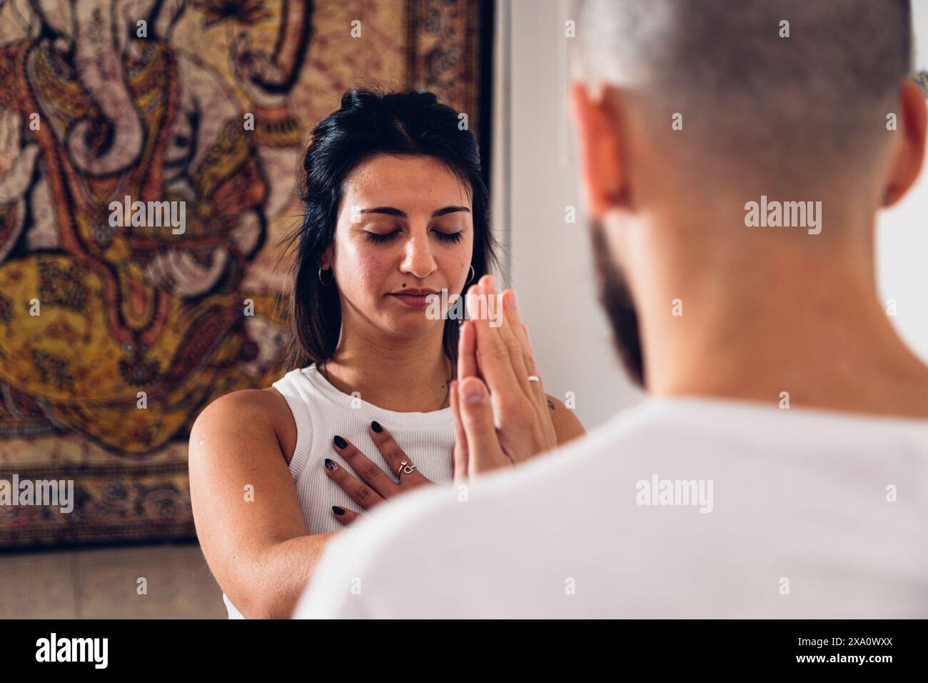 Young couple touching hands while practicing yoga posture together in the studio. Close view. Stock Photo