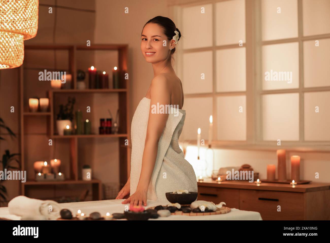 Young woman with plumeria flower in dark spa salon Stock Photo - Alamy