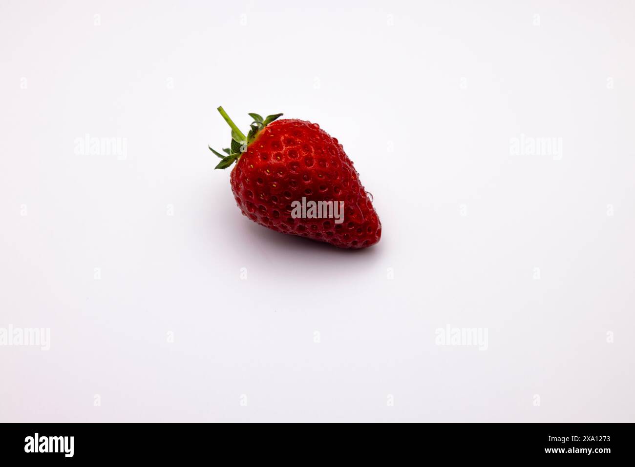 Ripe strawberry casting a shadow on white surface Stock Photo