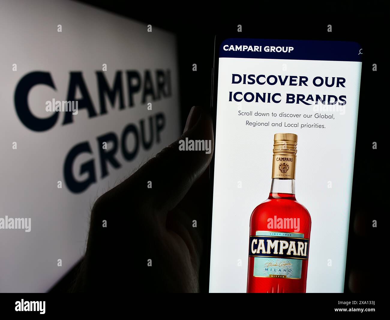 Person holding cellphone with webpage of Italian spirits company Davide Campari-Milano N.V. in front of logo. Focus on center of phone display. Stock Photo