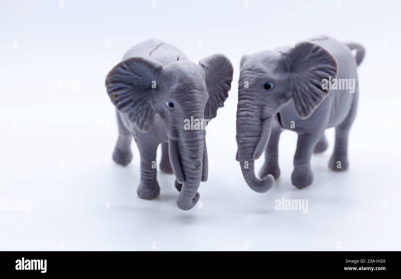A closeup of two plastic toy elephants against a white backdrop Stock