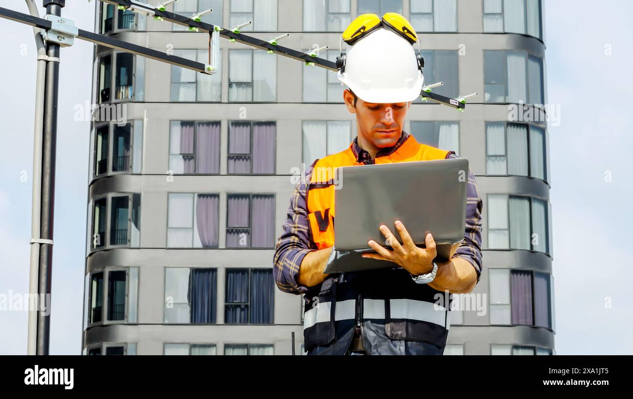 An engineer working on a laptop at a building site. Stock Photo