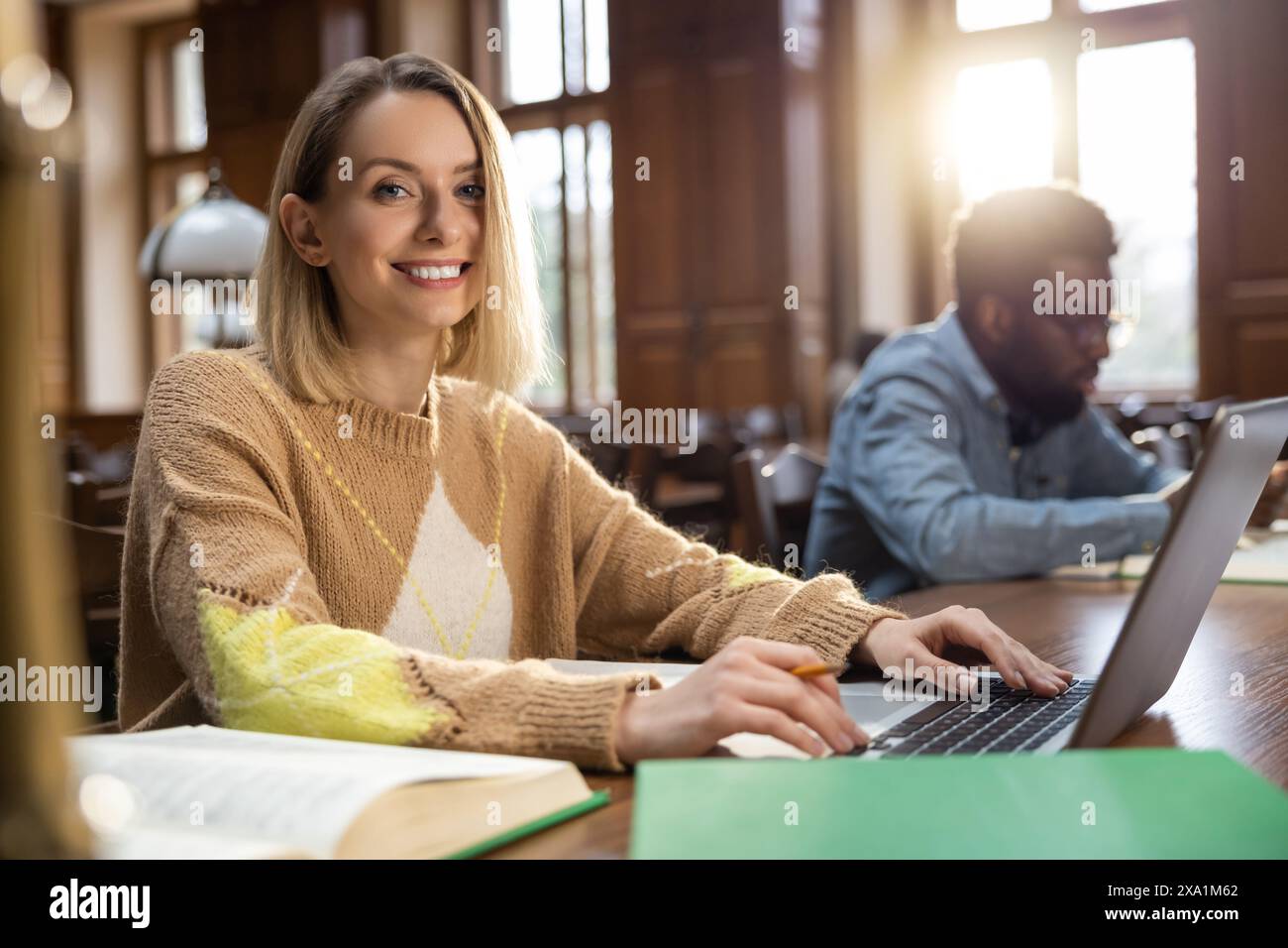 Blonde woman in the library. Blonde smiling woman at the laptop in the library Stock Photo