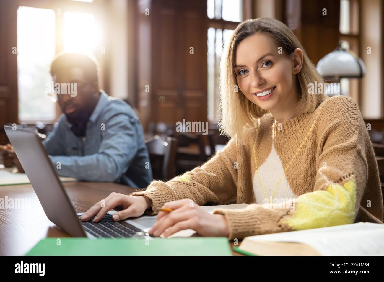 Blonde woman in the library. Blonde smiling woman at the laptop in the library Stock Photo