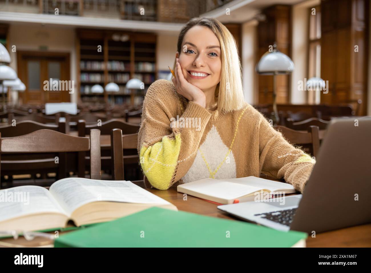 Blonde woman in the library. Blonde smiling woman at the laptop in the library Stock Photo