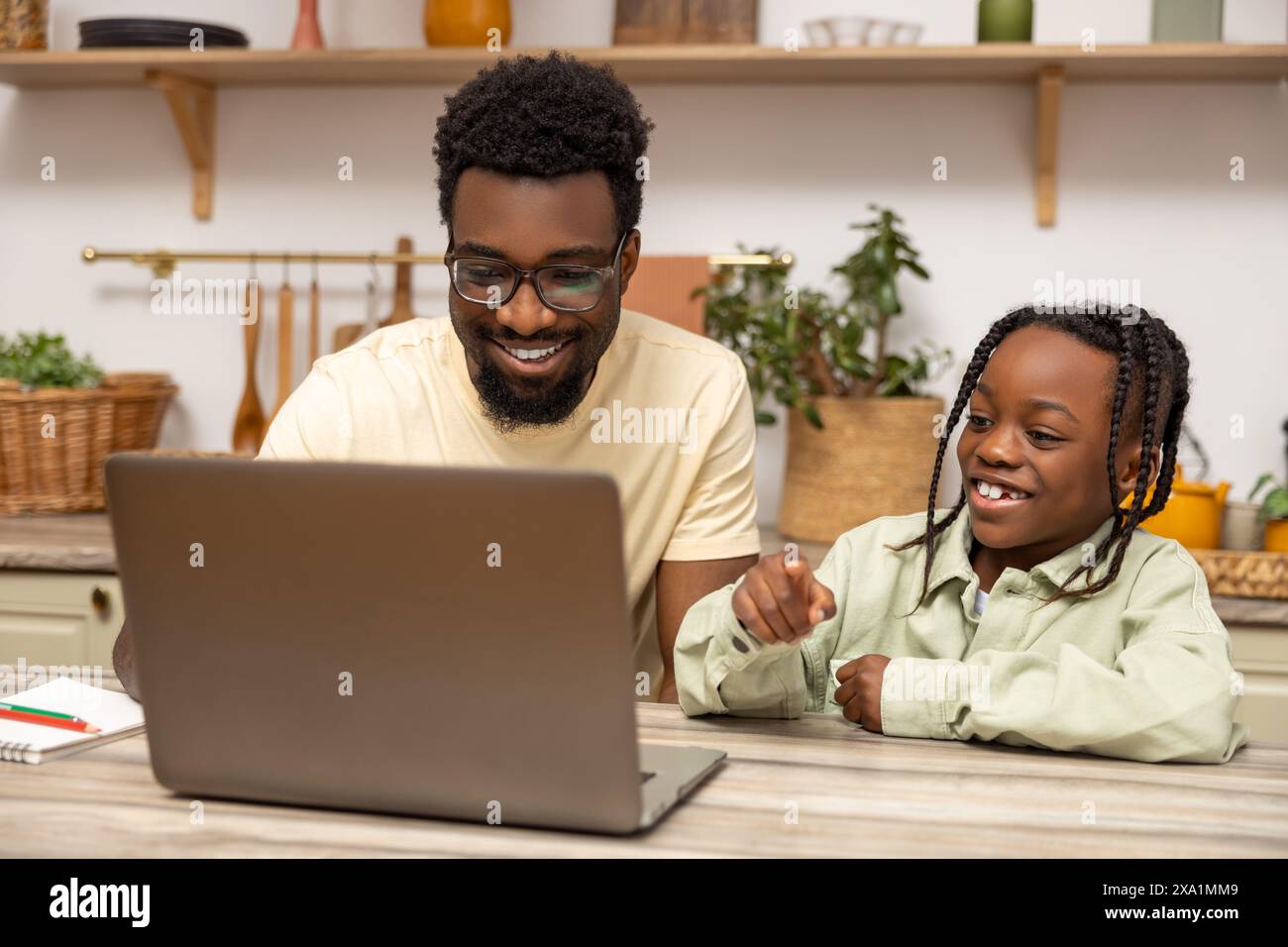 African American father helps his daughter with lessons during distance education at home Stock Photo