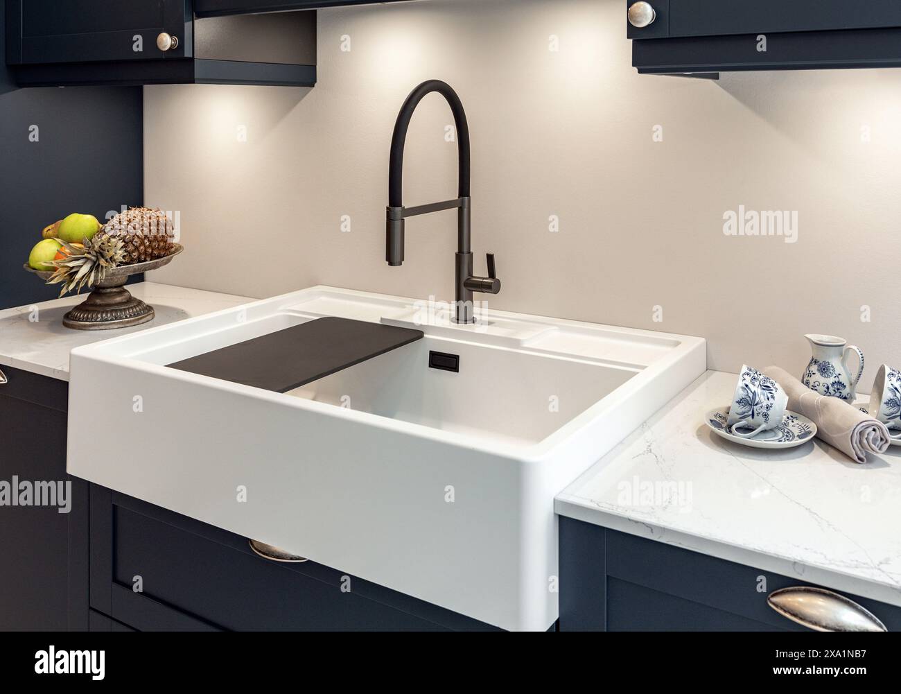 Modern black faucet and white kitchen sink in new kitchen with gray ...