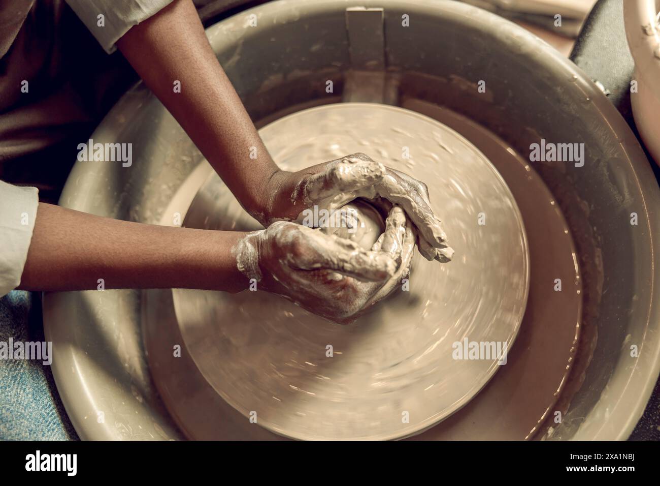 Process of creation. Close up picture of hands working with wet clay and molding its shape Stock Photo