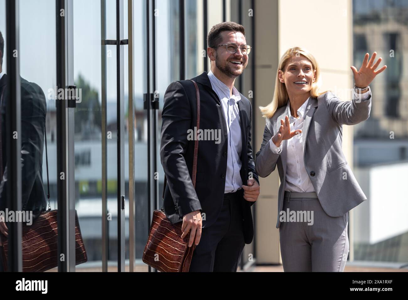 Cheerful man and woman wearing official style suits posing outdoor and talking about business ideas Stock Photo