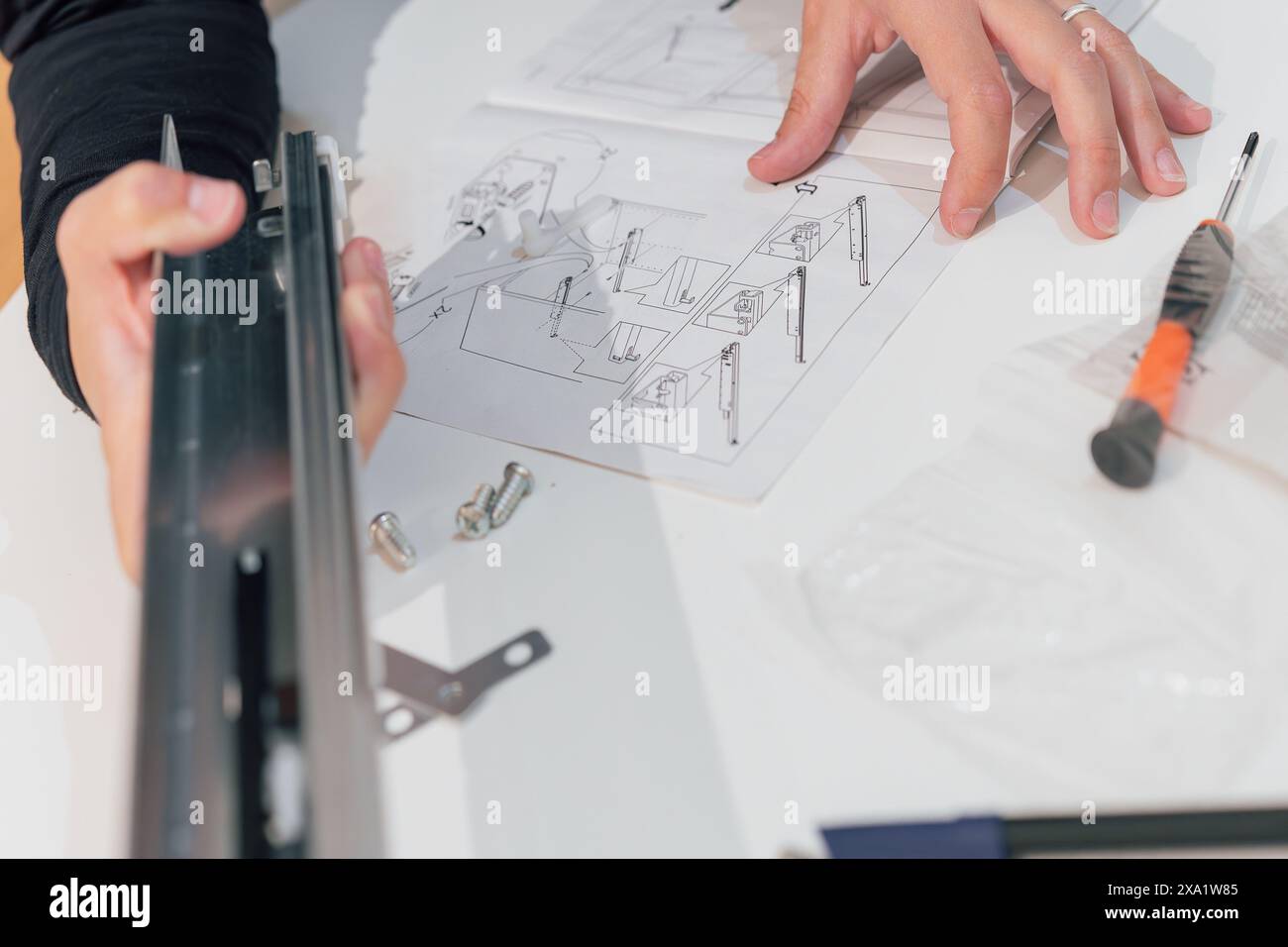 Woman's hands following instructions for assembling a piece of ...