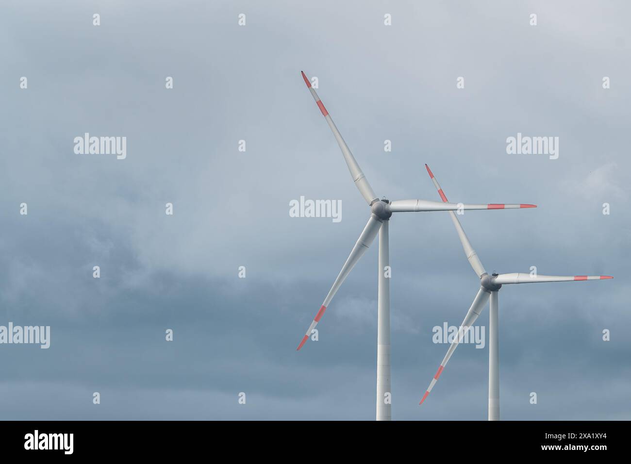 Two synchronous wind turbines under the dark cloudy sky Stock Photo - Alamy