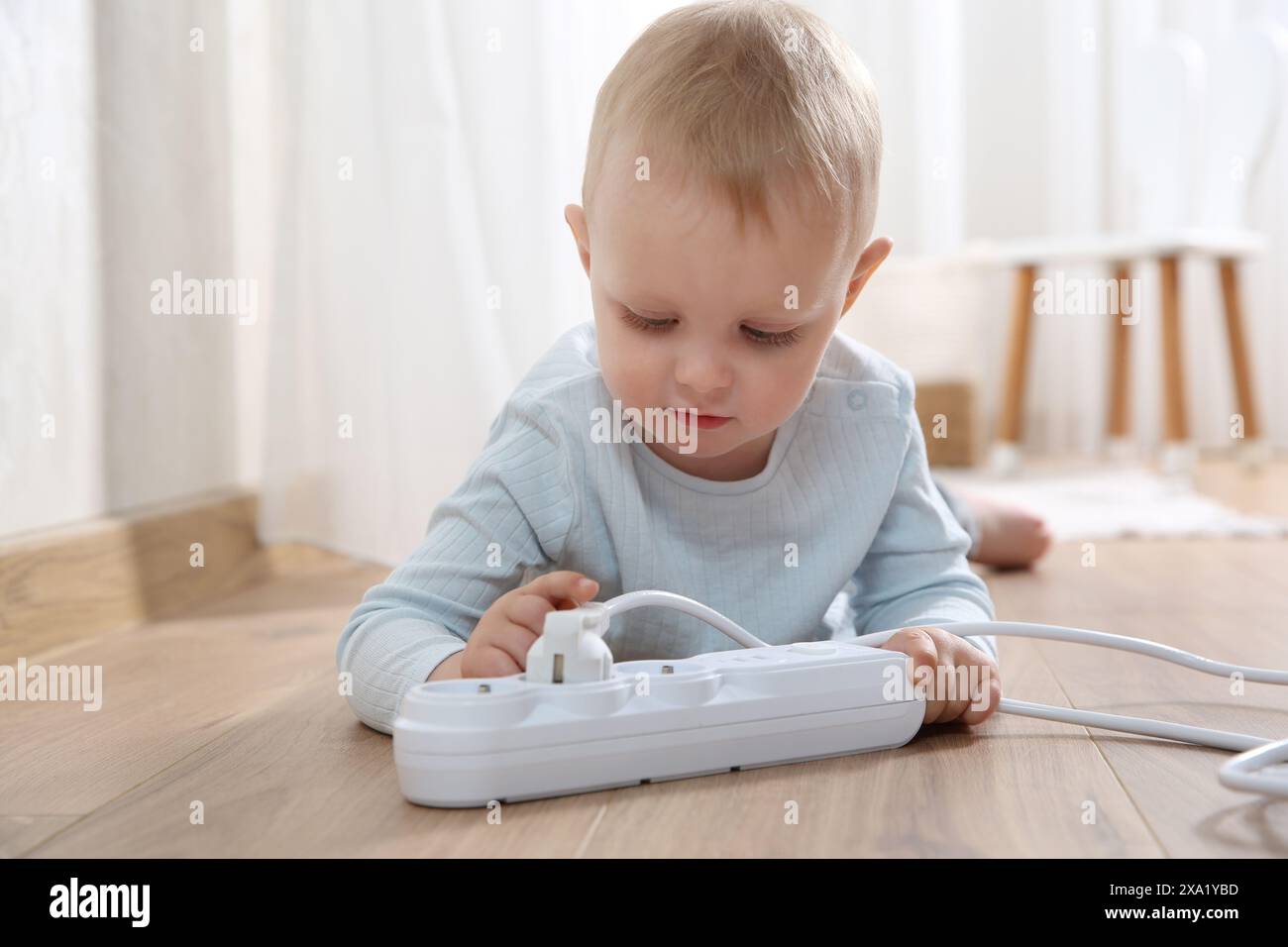 Little child playing with power strip and plug on floor indoors ...