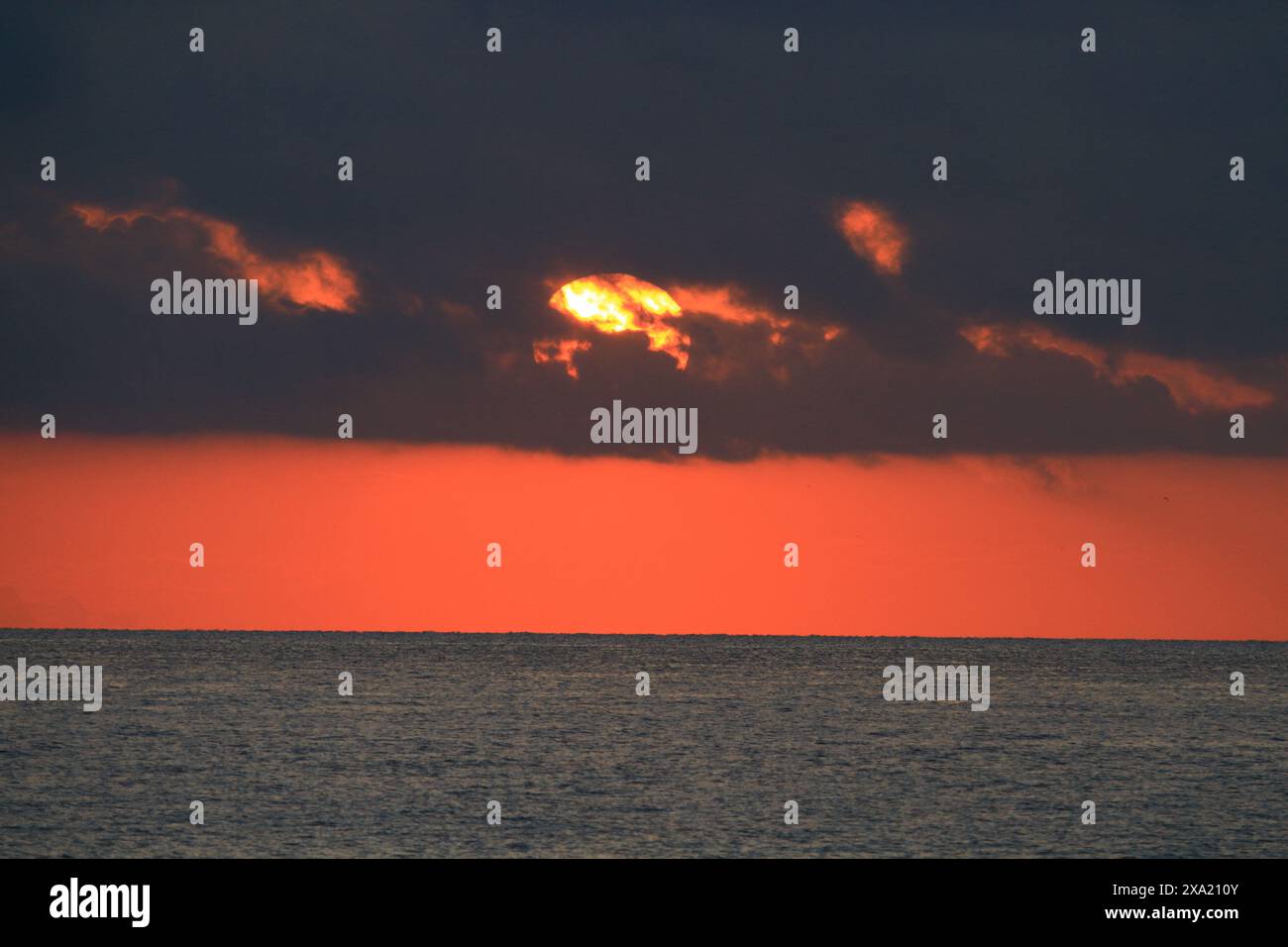 The sun setting over the ocean at dusk Stock Photo
