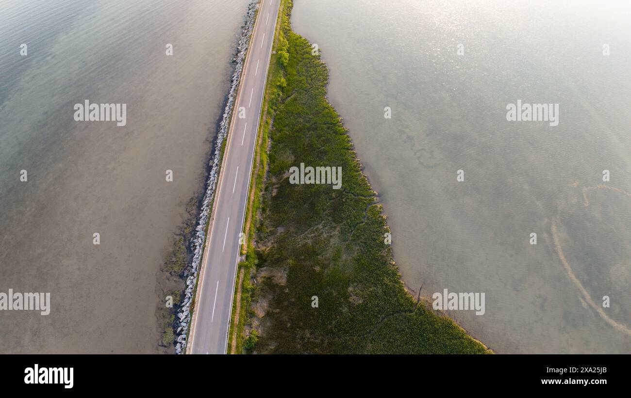 A scenic coastal road with ocean views and lush grass surroundings ...