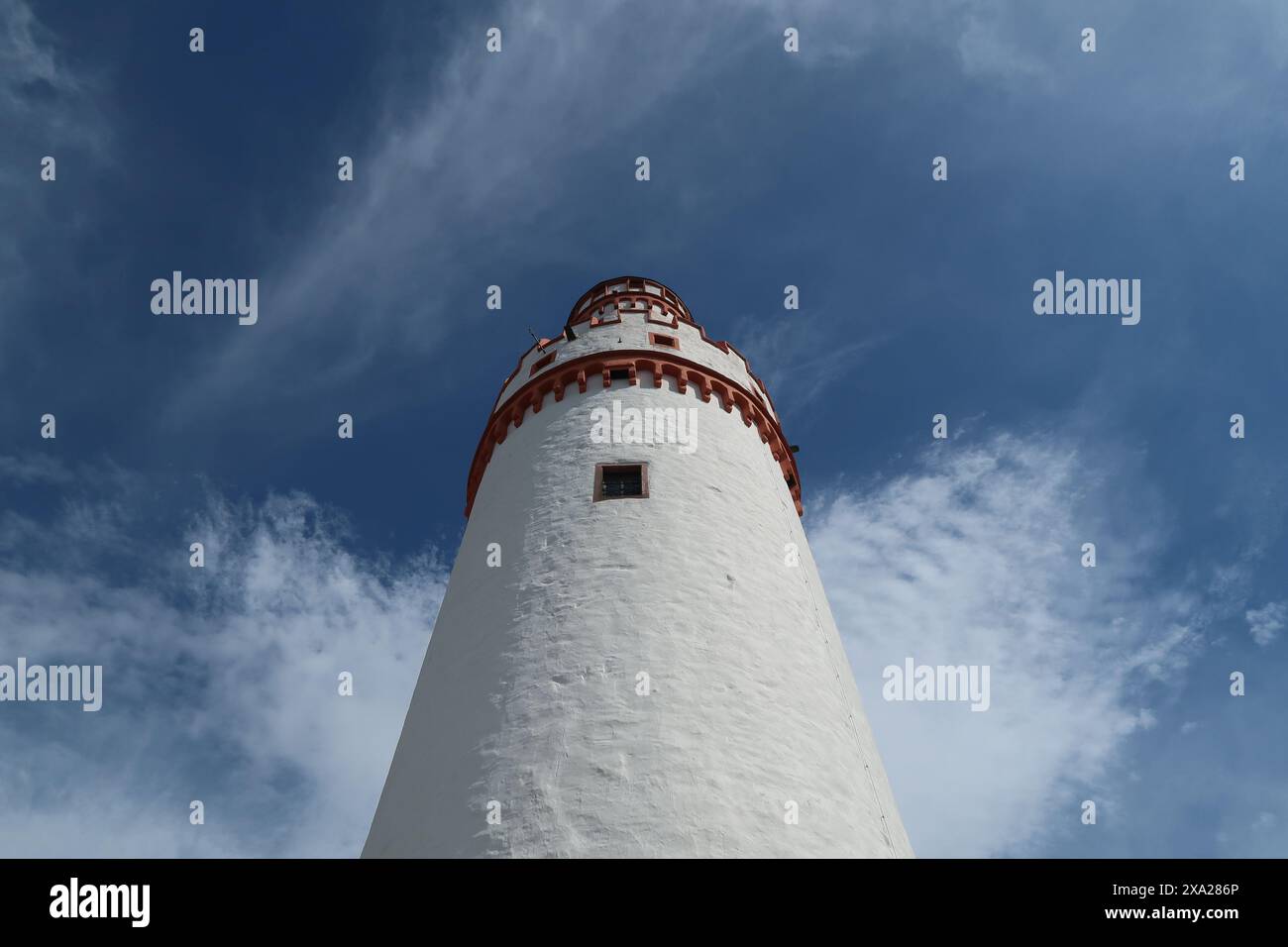 A white and red lighthouse tower stands out against blue sky Stock Photo