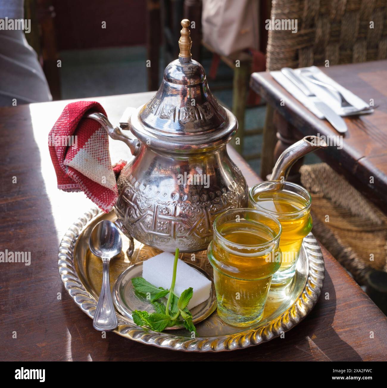 Morocco: Mint tea at a cafe in Djemaa El Fna (market square), Medina of Marrakesh, Marrakesh.  According to oral tradition, tea has been grown in China for more than four millennia. The earliest written accounts of tea making, however, date from around 350 CE, when it first became a drink at the imperial court.  Gunpowder green tea was introduced into North Africa by the British in the 18th and 19th centuries via Morocco and Algeria. Stock Photo