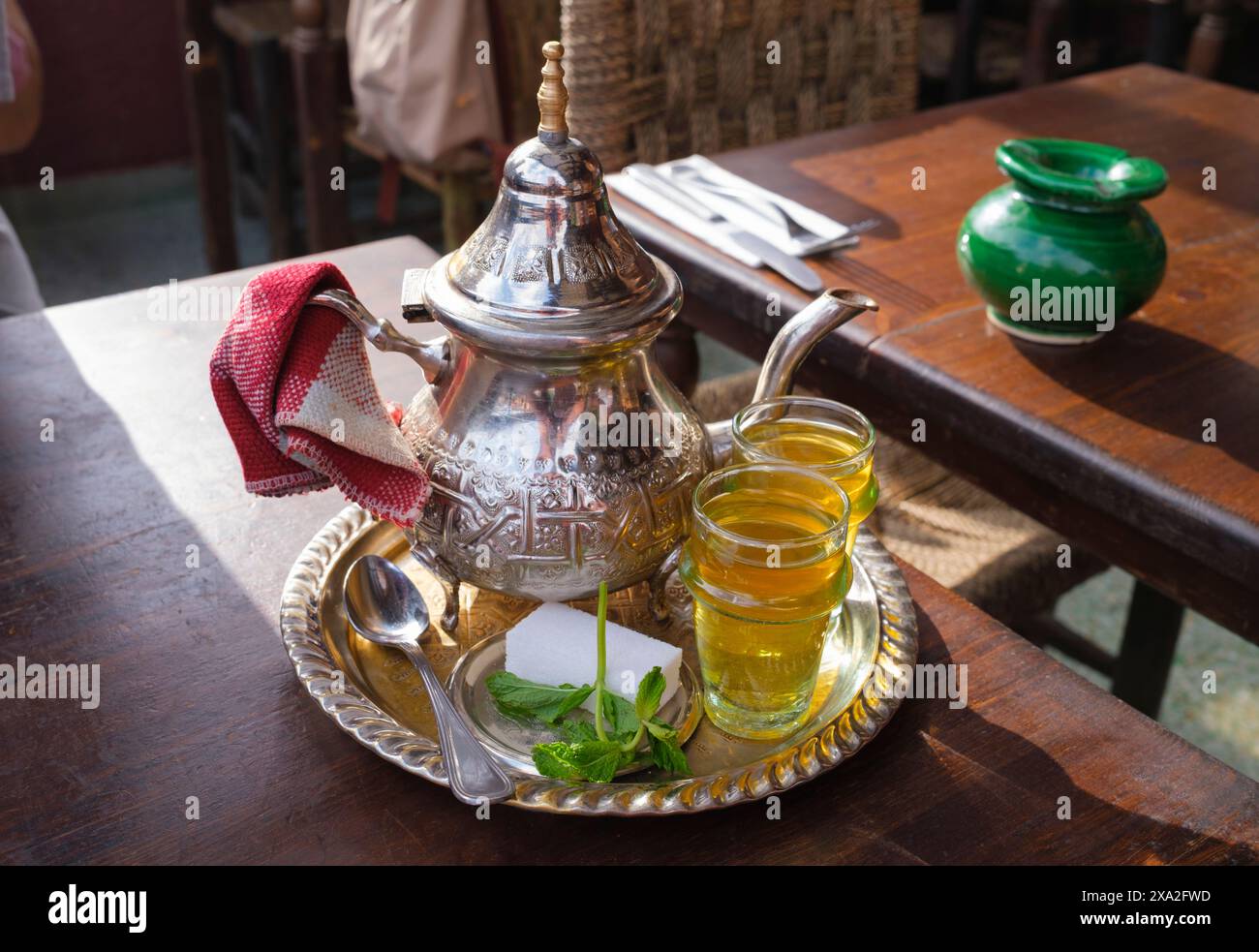 Morocco: Mint tea at a cafe in Djemaa El Fna (market square), Medina of Marrakesh, Marrakesh.  According to oral tradition, tea has been grown in China for more than four millennia. The earliest written accounts of tea making, however, date from around 350 CE, when it first became a drink at the imperial court.  Gunpowder green tea was introduced into North Africa by the British in the 18th and 19th centuries via Morocco and Algeria. Stock Photo