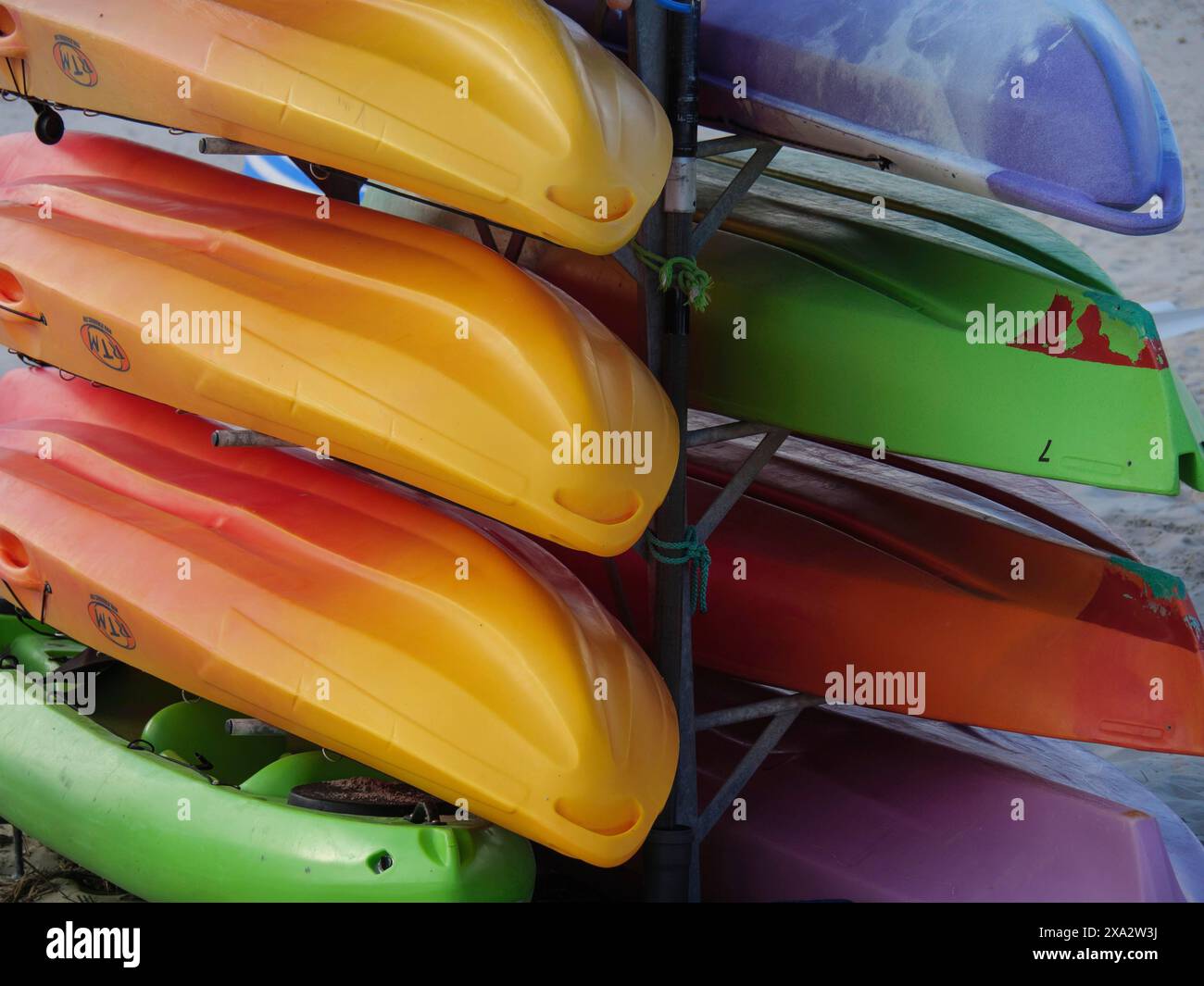 Colourful kayaks are stacked on top of each other and stored on a beach, Baltrum Germany Stock Photo