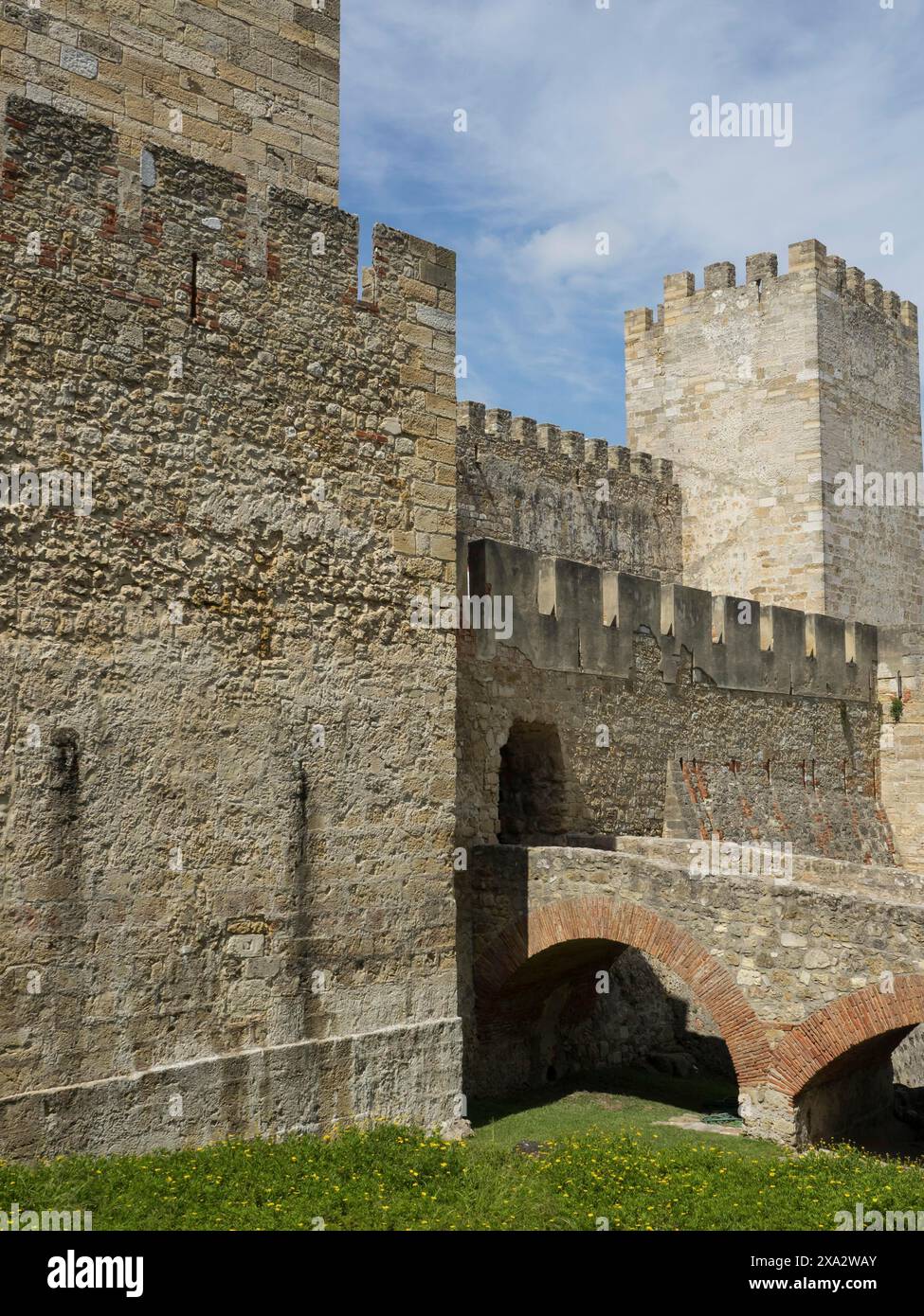 A medieval castle with high stone walls and a gate leading over a stone ...