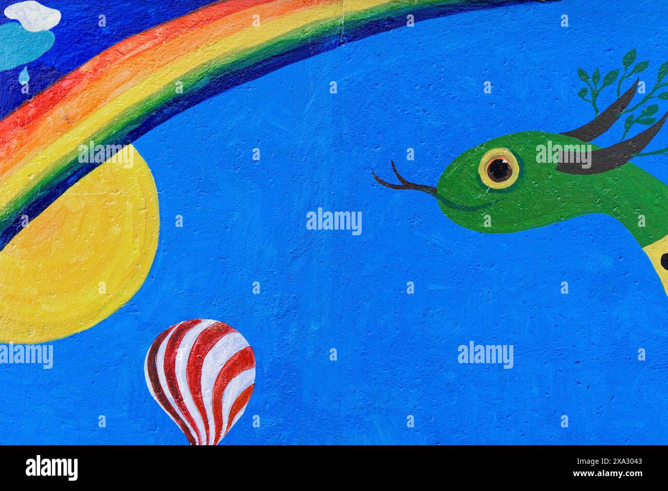 Colourful mural with a snake, sun, rainbow and a hot air balloon under a clear sky, mural, East Side Gallery, Mauergalerie, Berlin, Germany Stock Photo