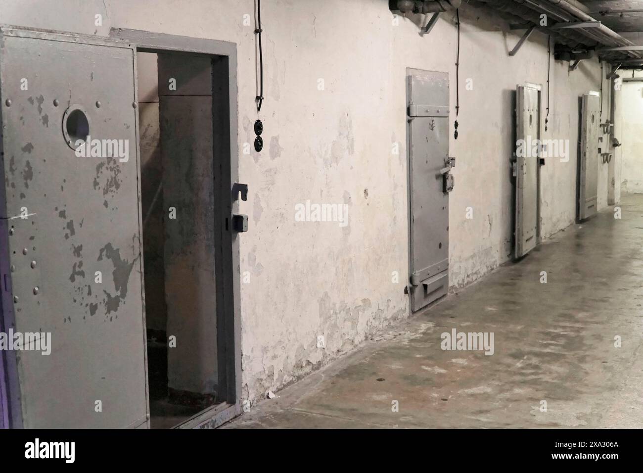 Prison corridor with several robust metal cell doors and light switches. Gloomy, deserted atmosphere, Berlin-Hohenschoenhausen Memorial, former Stock Photo
