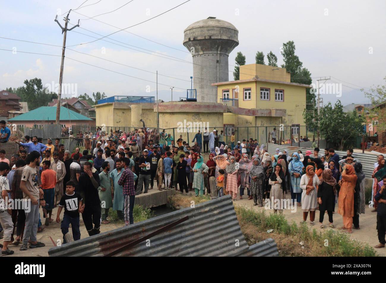 A large crowd gathers in an urban area near a water tower and various buildings, engaged in an event or observation, Encounter, Pulwama, Jammu and Stock Photo