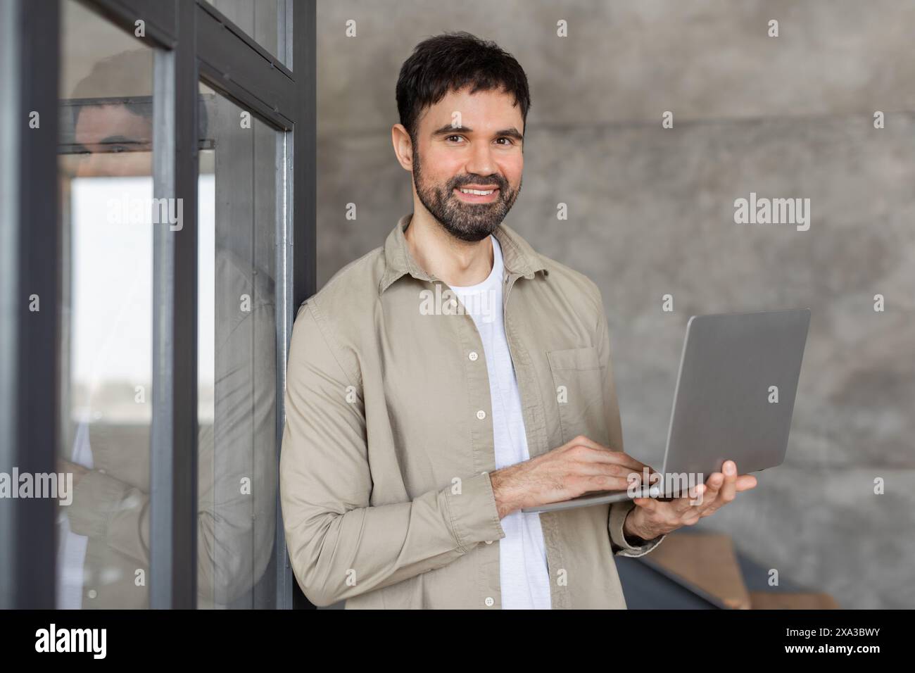 Smiling Man Using Laptop in Modern Office Building Stock Photo