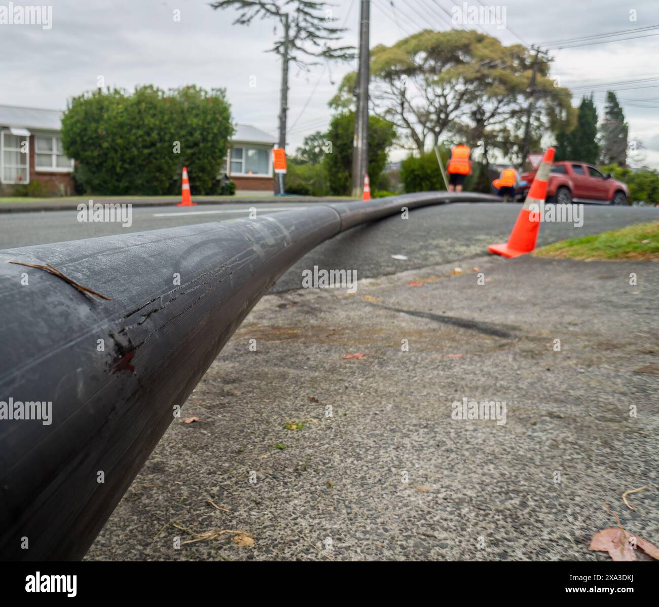 Unrecognizable workers moving a long pipe at a road construction site. Auckland. Stock Photo