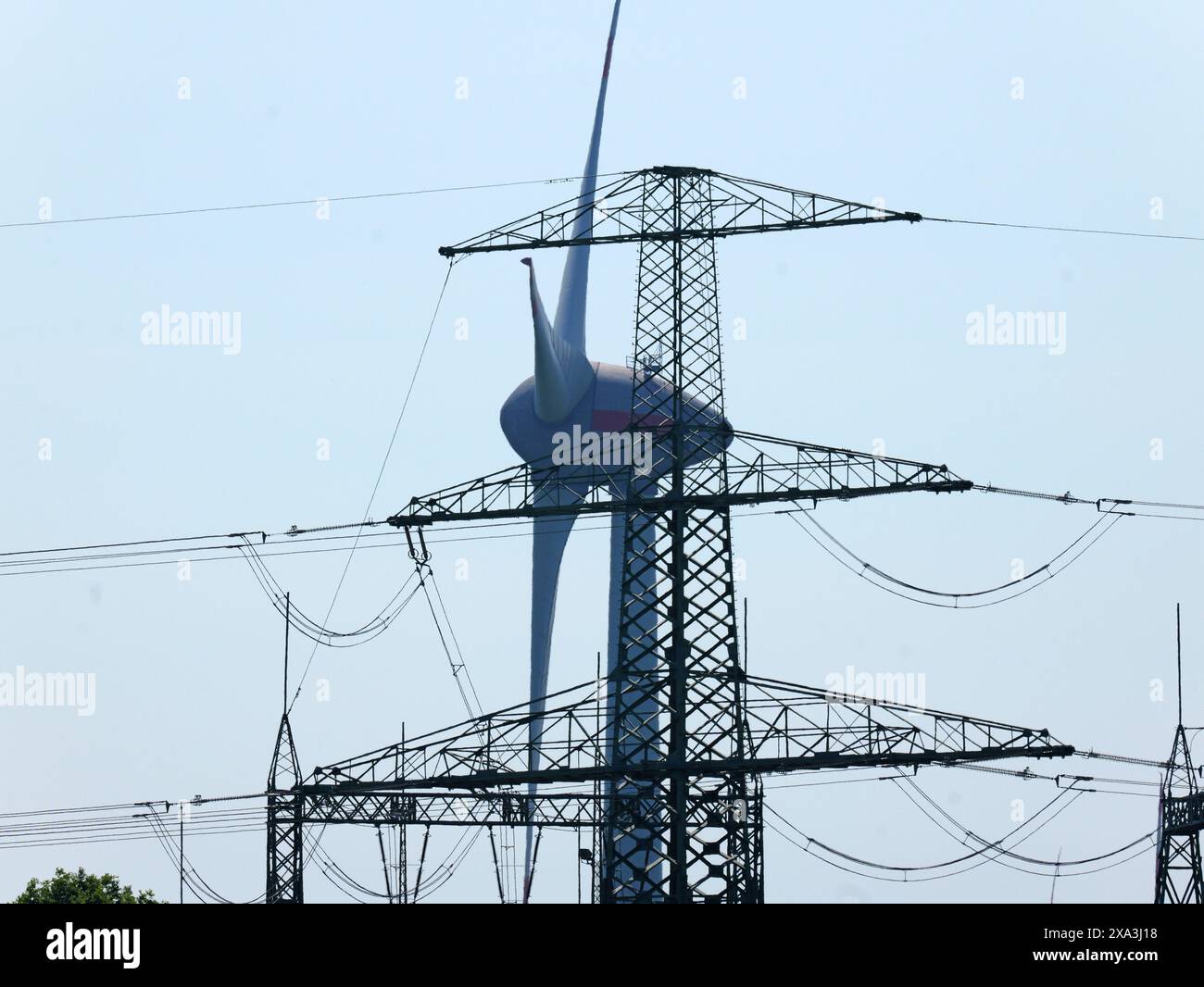 A photo of a wind turbine and a high voltage mast symbolizes sustainable energy generation and the transition to renewable energy sources. Stock Photo