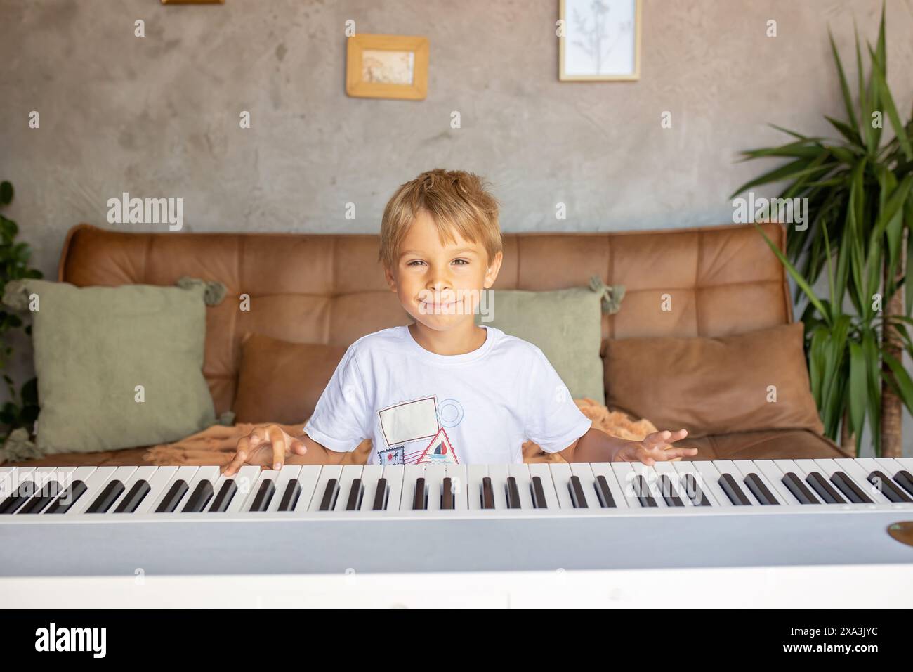 Child, blond boy, playing piano at home, learning Stock Photo