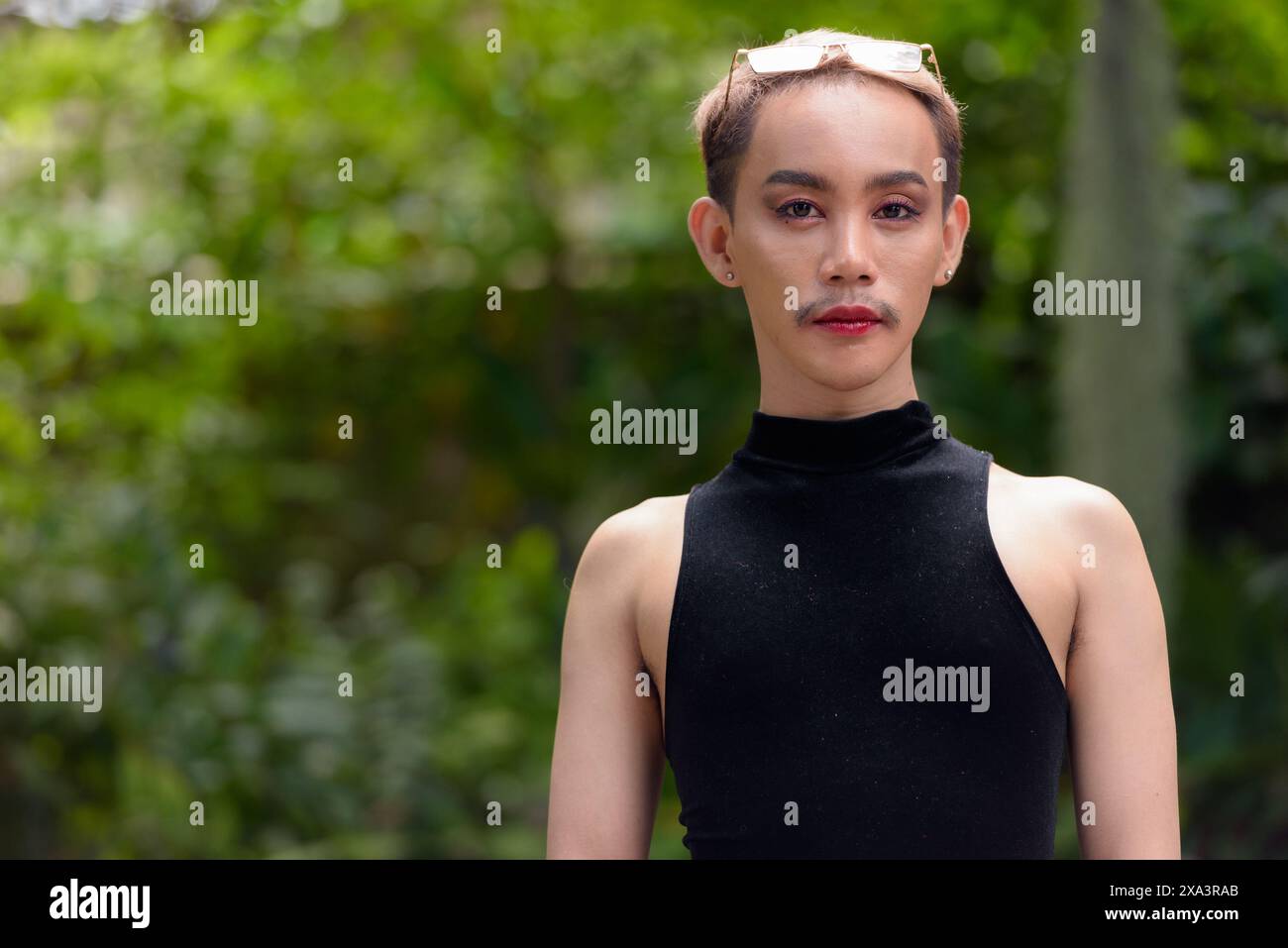 Portrait of beautiful Asian queer LGBT community supporter man with mustache wearing lipstick and jumpsuit Stock Photo