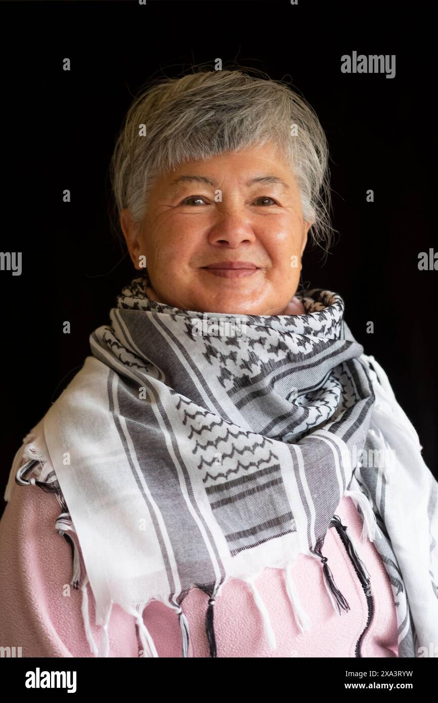 An elderly Eurasian Chinese/Italian woman wearing a keffiyeh to demonstrate her support for Palestine Stock Photo