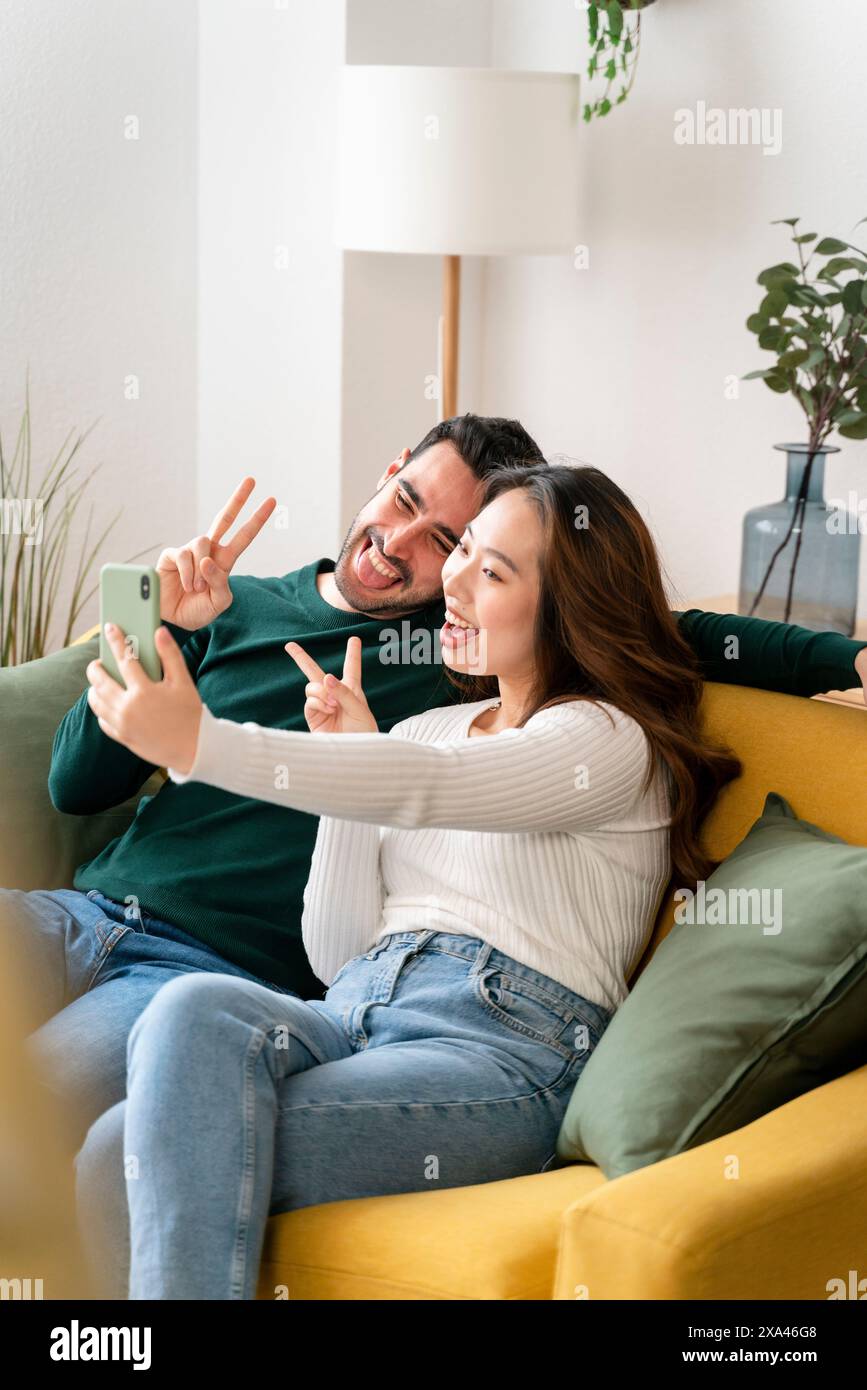 Couple taking a selfie on a yellow couch. Stock Photo