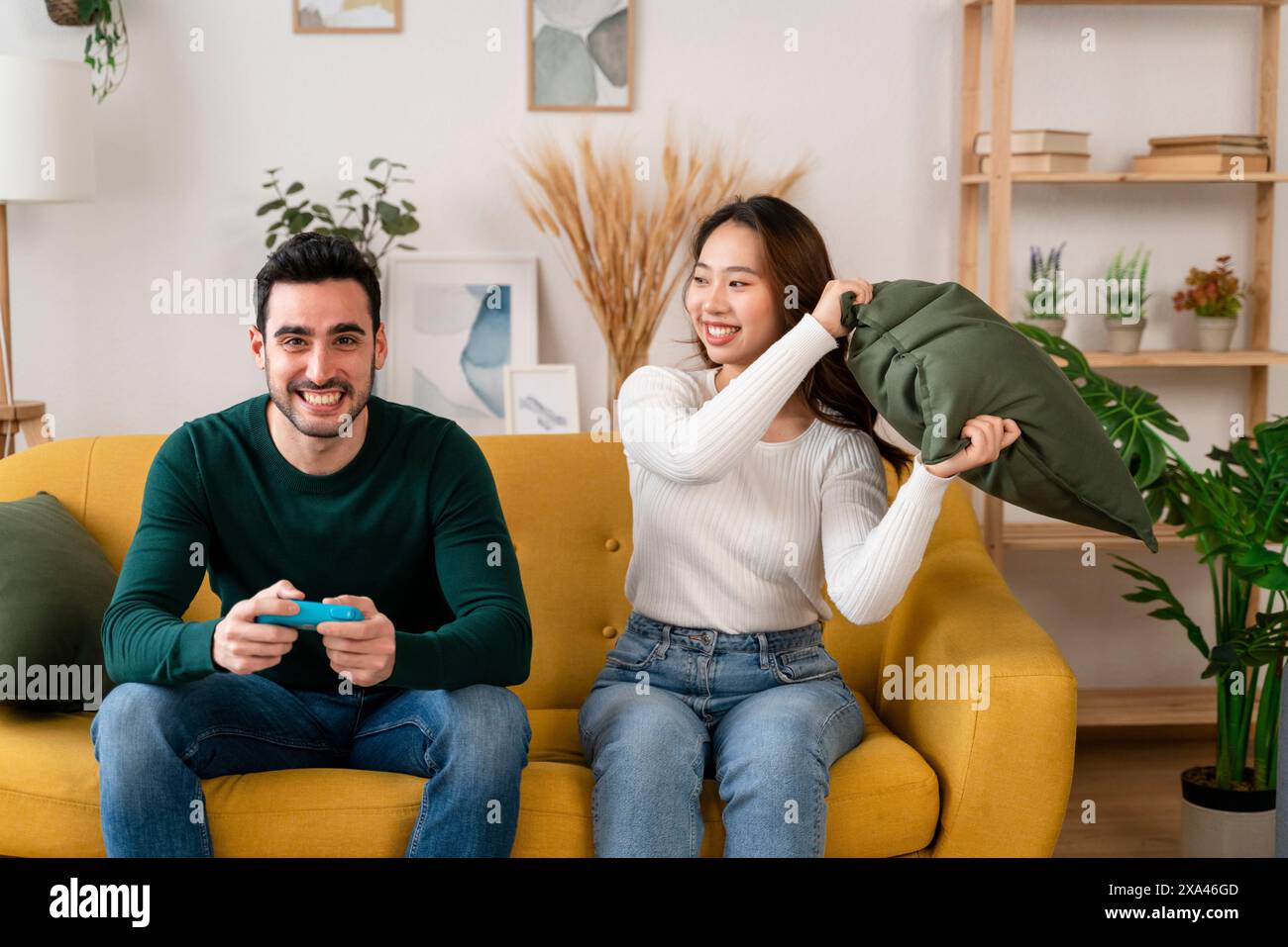 Playful couple on a yellow sofa with a video game controller Stock Photo